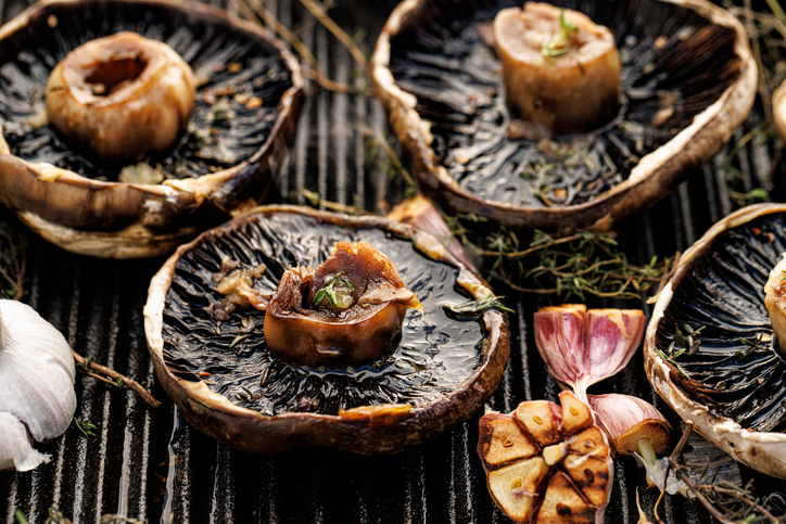 Grilled portobello mushrooms with herbs and garlic on a grill plate, close-up