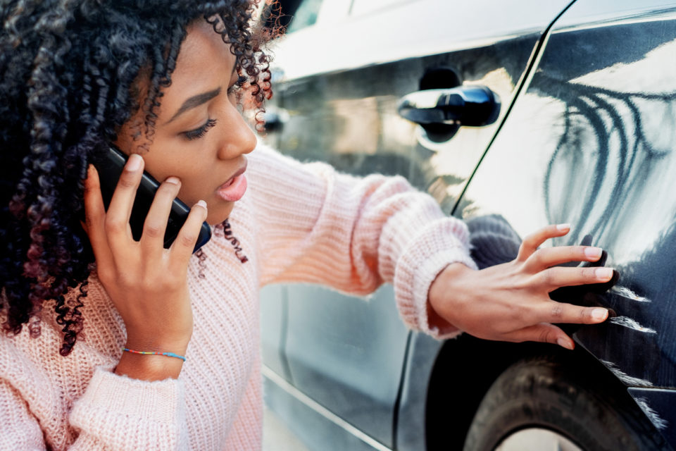 Woman examines damage on the side of her car