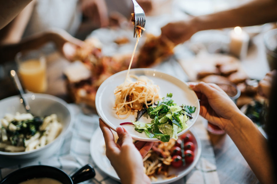 Family passing and sharing food across table.