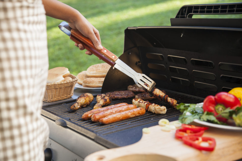 Barbecue grill with meat, vegetables, and bread.