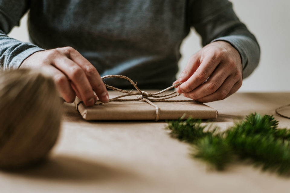 Close-up of male hands wrapping present with eco-friendly materials.