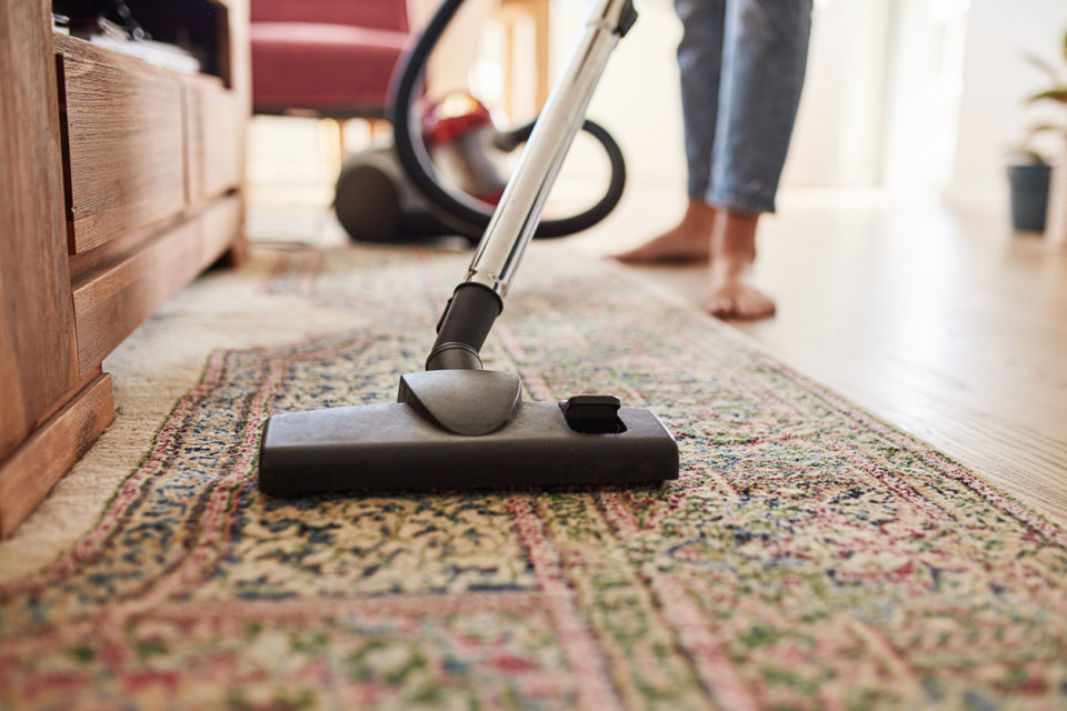 Shot of a young woman vacuuming the living room at home