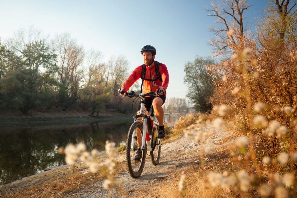 Young bearded man cycling on a sunny day