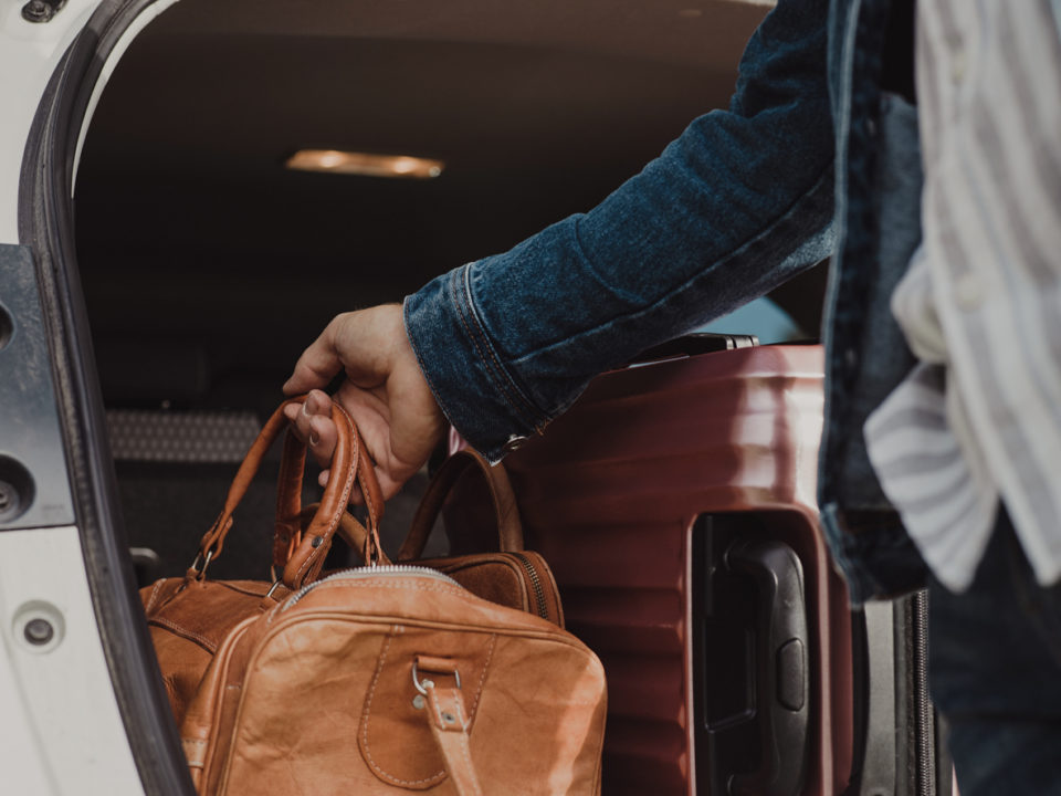 Man packing in his luggage suitcase in his car ready for road trip