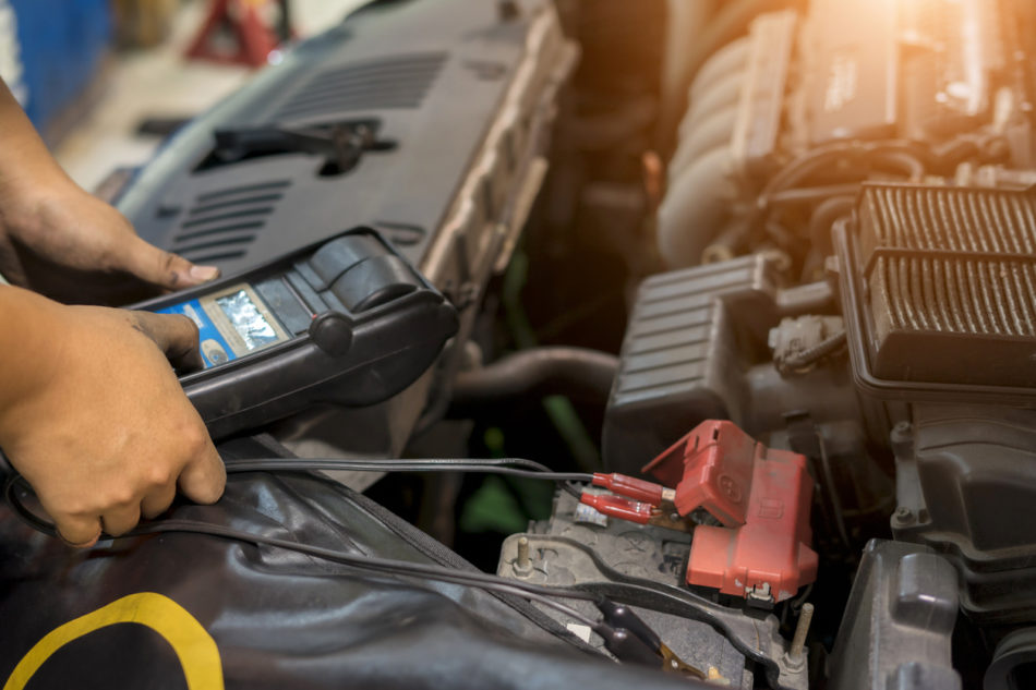 Mechanic use voltmeter checking voltage of car battery