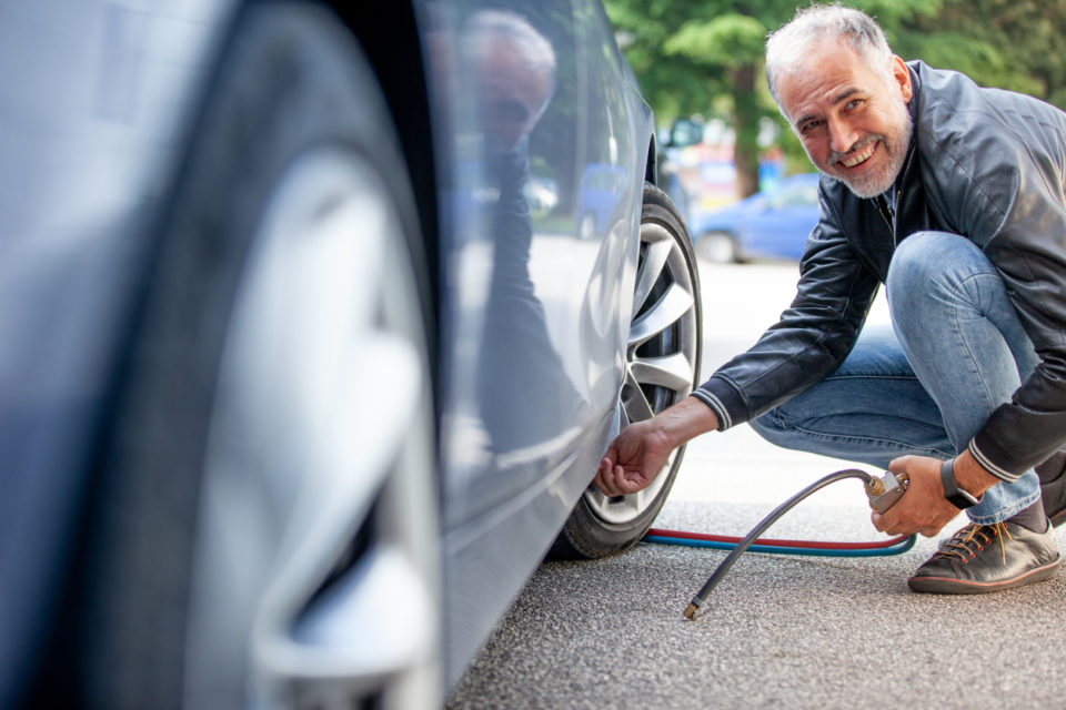 Smiling Mature Man Inflating Car Tires Outdoors