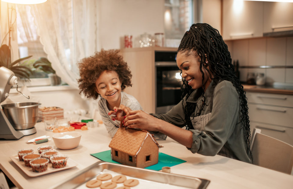 Mother And Her Daughter Assemble Gingerbread House