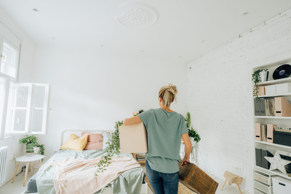 young woman arranging the bedroom of her new apartment