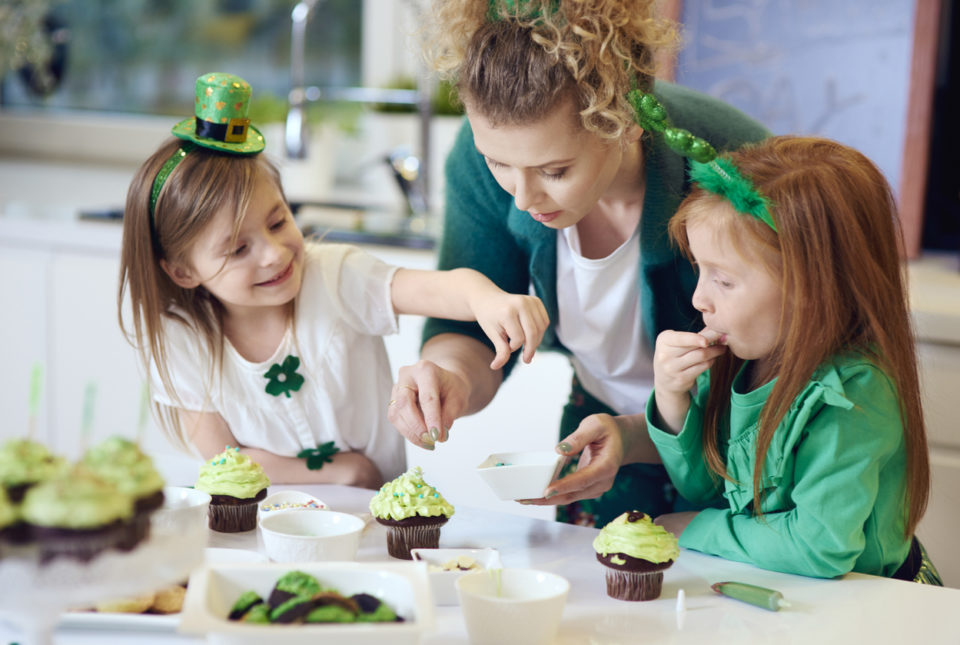 A woman and her children decorate St. Patrick's Day cupcakes