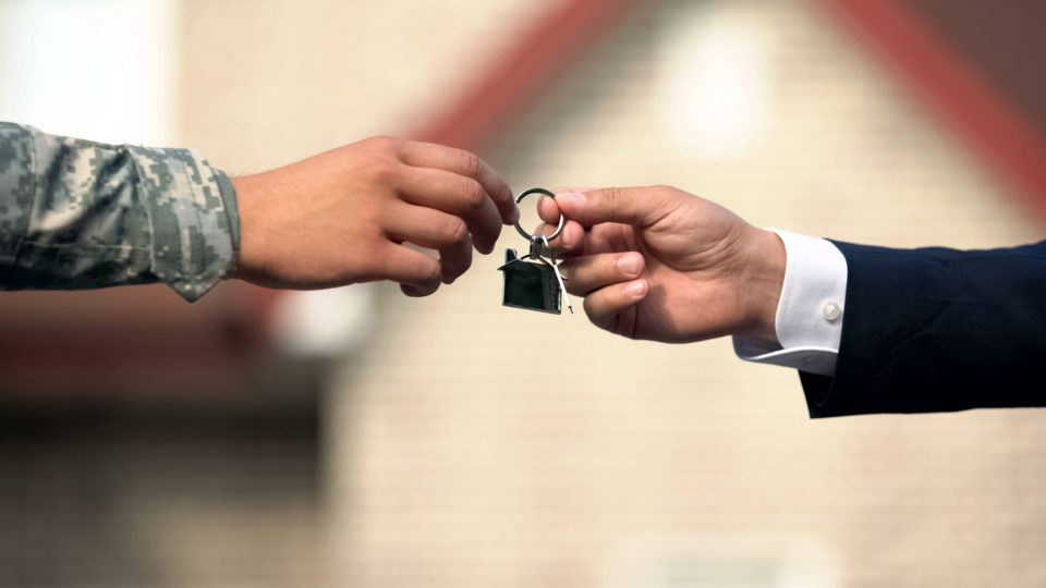 a man giving house key to man in military uniform, state support