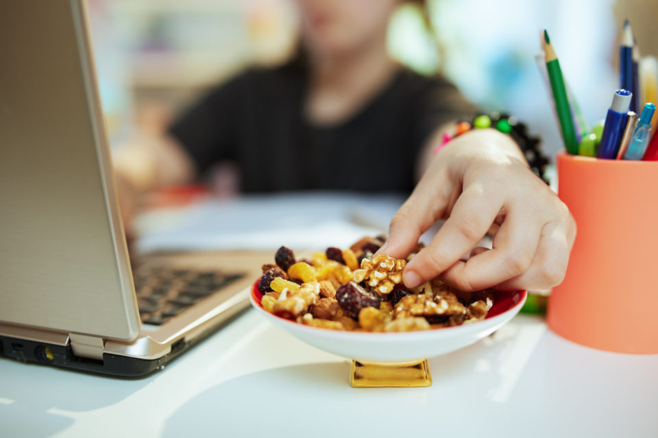 Modern school girl distance learning and eating healthy snack