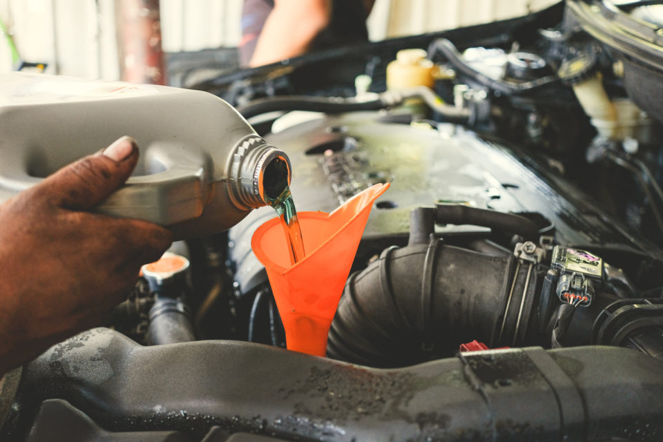 Car service. Car technician pouring the fresh transmission oil at the car service station.