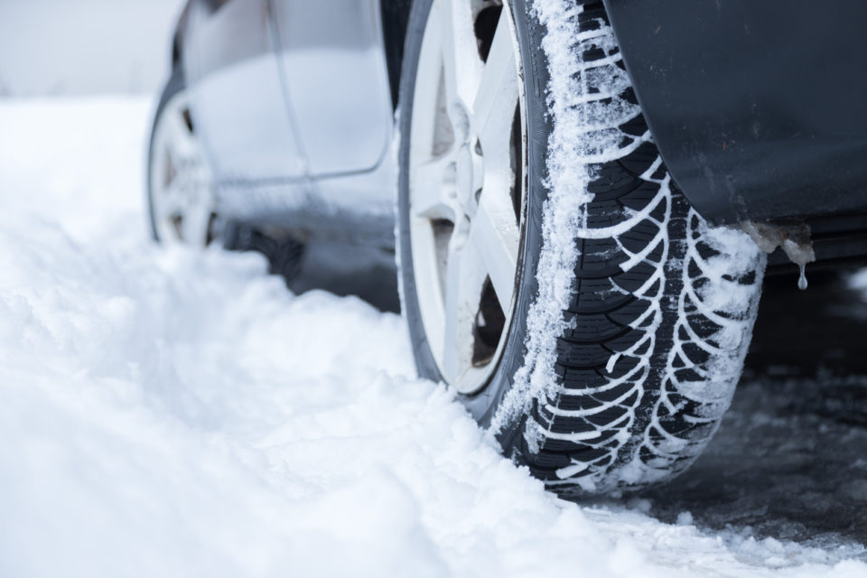 A profile view of a car driving in powdery snow