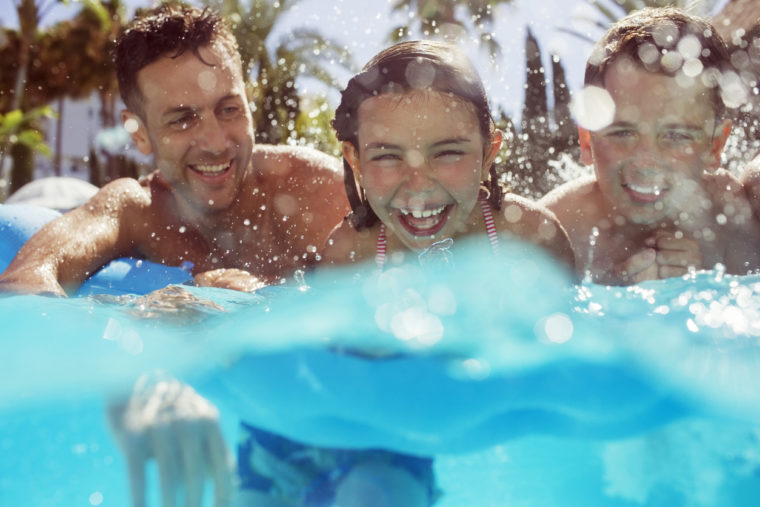 Father swimming with his two children in swimming pool