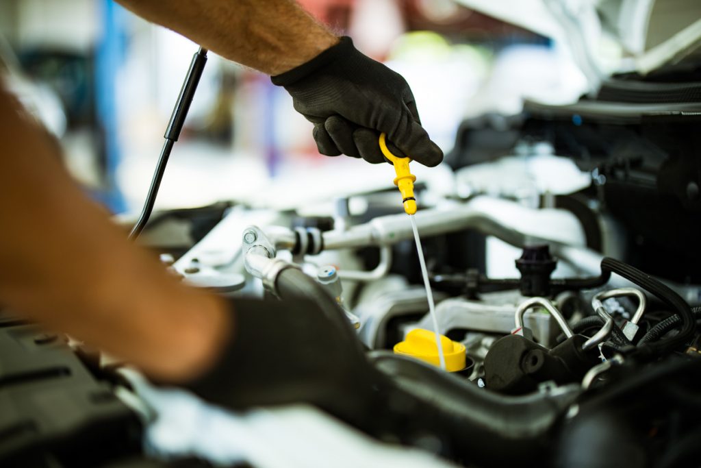 Close up of mechanic examining car oil in a repair shop.