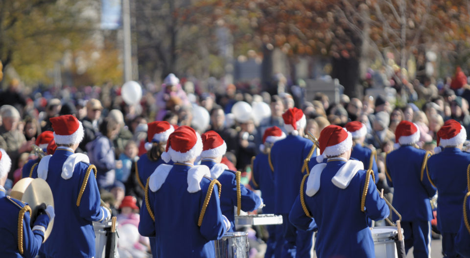 daytime parade with band in blue uniforms and Santa hats