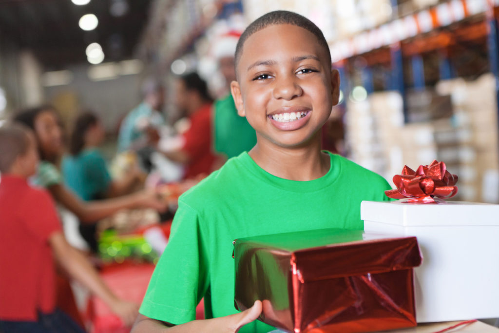 Happy little boy donating Christmas gifts at charity toy drive