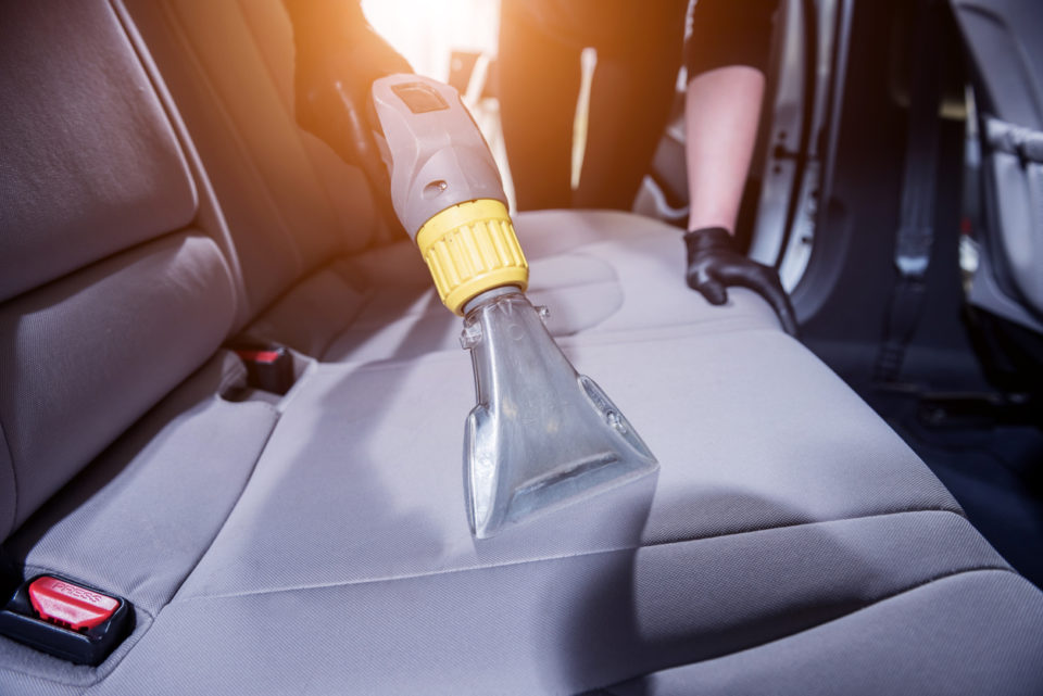 Worker cleans car interior with vacuum cleaner