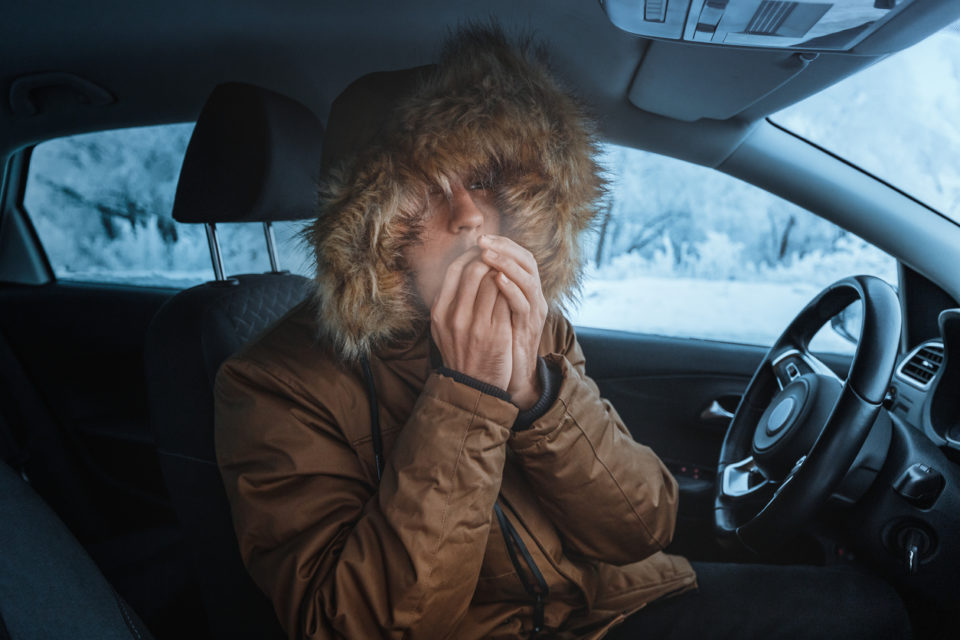 Man in jacket tries to keep warm in his car